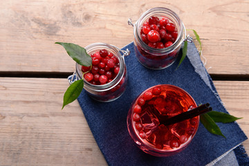 Compote with red currant in glassware on jeans cloth on wooden background