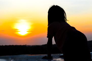 Fototapeta premium Girl standing on the top of building overlooking sunrise
