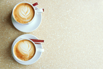 Cups of cappuccino with heart on foam on table in cafe