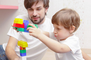 Father and son play with building kit