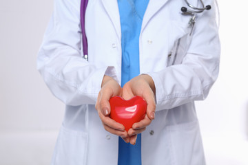 Doctor with stethoscope holding heart, isolated on white