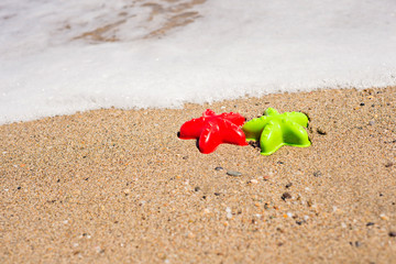 Red and green starfish-shaped molds on the sand