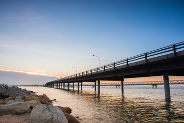 Fototapeta na wymiar Concrete Bridge over sea water with sunrise