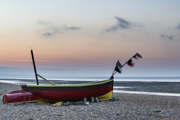 Landscape image of small fishing boats on beach at sunrise in Sp