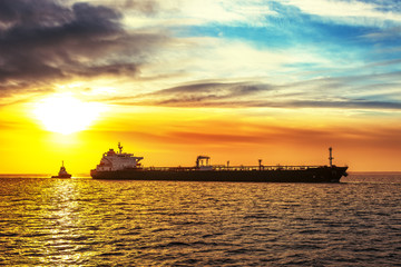 Tugboat pulling the tanker at sea in the morning.