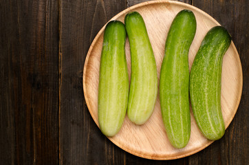 Fresh cucumber on wooden plate