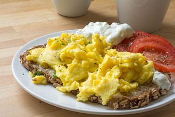 scrambled eggs on rustic bread with tomatoes and curd cheese cre