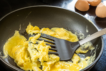 frying scrambled eggs in a pan black