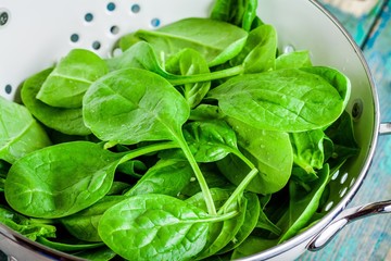 raw fresh spinach in a white colander closeup