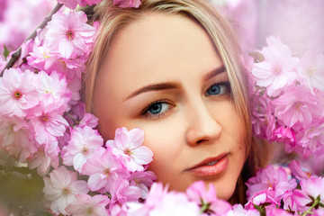 Fashion portrait of sexual beauty blonde in blooming pink flower