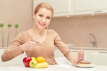 Smiling lady sits between fruit and dessert