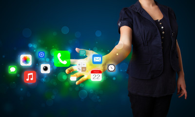 Young businesswoman pressing colorful mobile app icons with boke