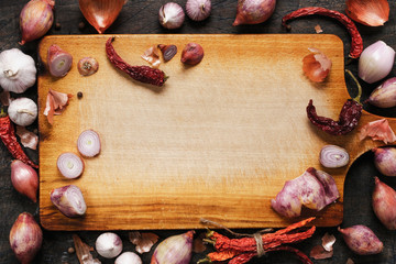 Wooden board with onions, garlic and pepper background