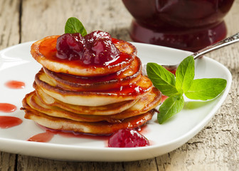 Hot pancakes with strawberry jam and mint leaves, selective focu