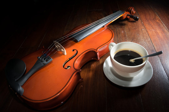 coffee cup with violin on wood surface.