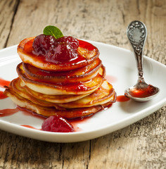 Hot pancakes with strawberry jam and mint leaves, selective focu