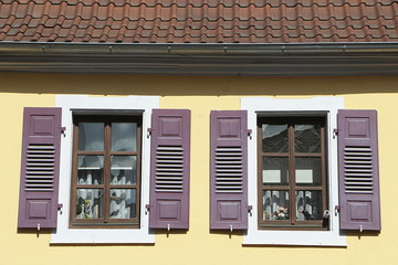 Zwei Fenster mit lila Fensterläden