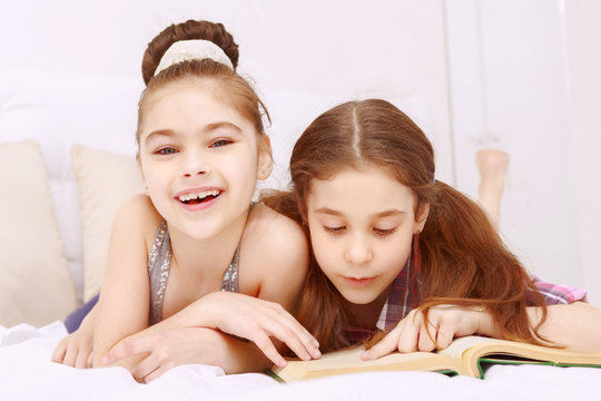 Pair of little girls reading book