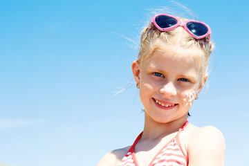 cute girl applying suntan cream on her face .