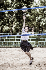 Cute Thai schoolgirl is playing beach volleyball in school unifo