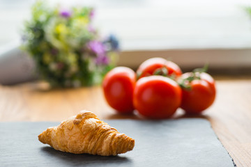 French tasty croissant on a wooden table near the window