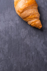 Tasty french croissant on a black stone plate