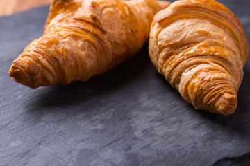 Tasty french croissant on a black stone plate