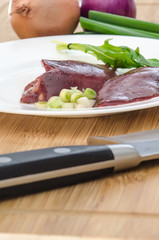 Raw chicken liver with vegetables on wooden background