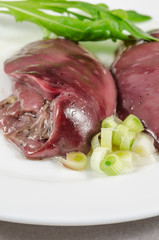 Raw chicken liver with vegetables at white plate