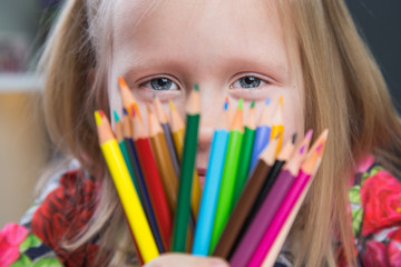 Small young girl drawing pictures with color pencils
