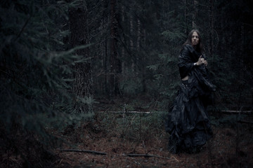 man with long hair in the dark forest