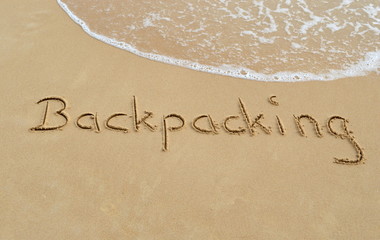Fototapeta na wymiar Text 'Backpacking' in the sand