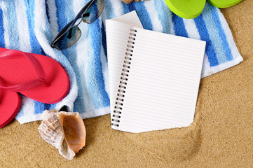 Notebook diary journal or note pad on a sunny beach sand background with seashells and accessories summer holiday vacation space for copy text photo
