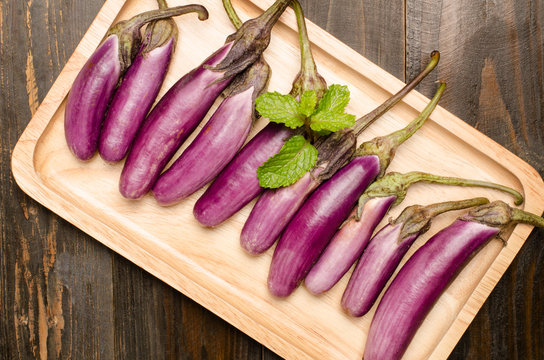 Fresh eggplants on wooden plate