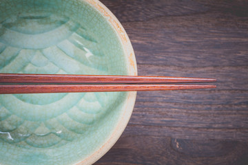  chopsticks and celadon green ceramic on wood table background