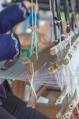 Woman weaving white pattern on loom