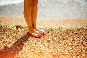 Woman's legs in slippers on the beach