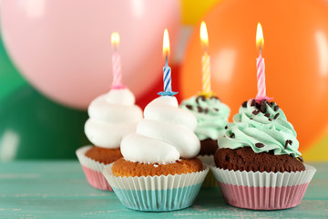 Delicious birthday cupcakes on table on bright background