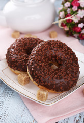 Delicious donuts with icing on plate on wooden background