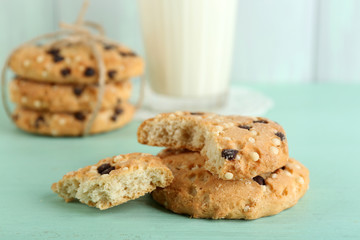 Tasty cookies and glass of milk on color wooden background