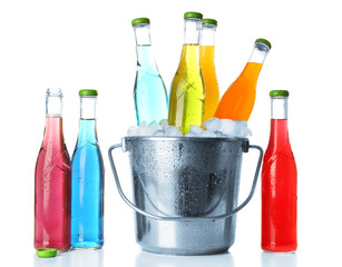 Bottles of tasty drink and metal bucket with ice isolated on white