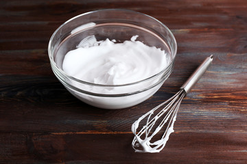 Fototapeta na wymiar Whipped egg whites for cream on wooden background