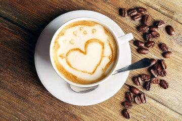 Cup of coffee latte art with grains on wooden background