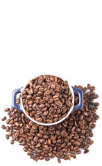Roasted coffee beans in a blue ceramic pot over white background
