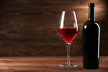Wineglass and bottle on wooden background