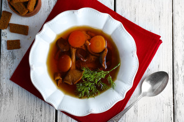 Mushroom soup on wooden table with napkin, top view