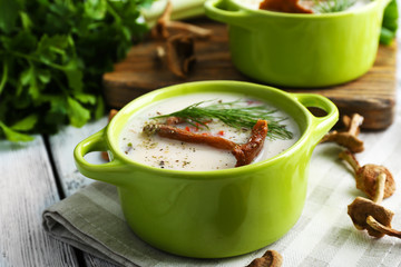 Mushroom soup with greens on wooden table, closeup