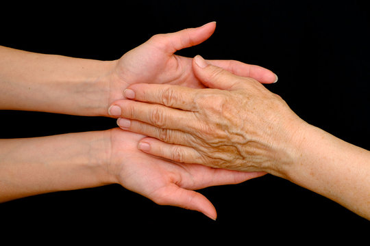 Old woman and young woman holding hands together