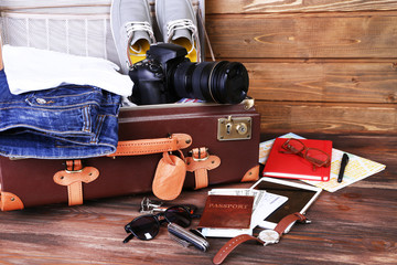 Packed suitcase of vacation items on wooden background