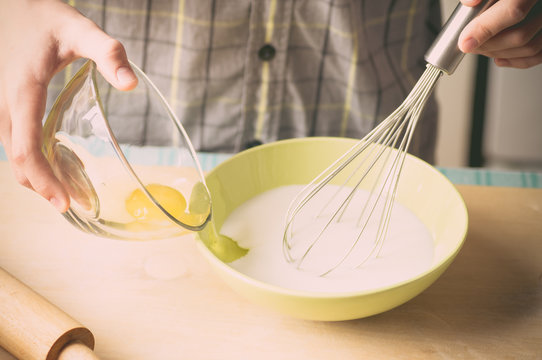 Hands of a young boy with a whisk and eggs